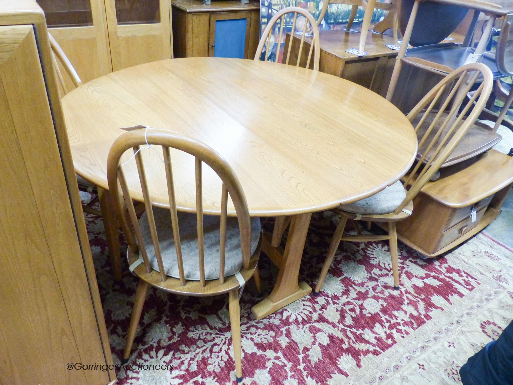 An Ercol elm circular drop leaf dining table, 126cm diameter, height 71cm together with four Ercol elm and beech shaker dining chairs